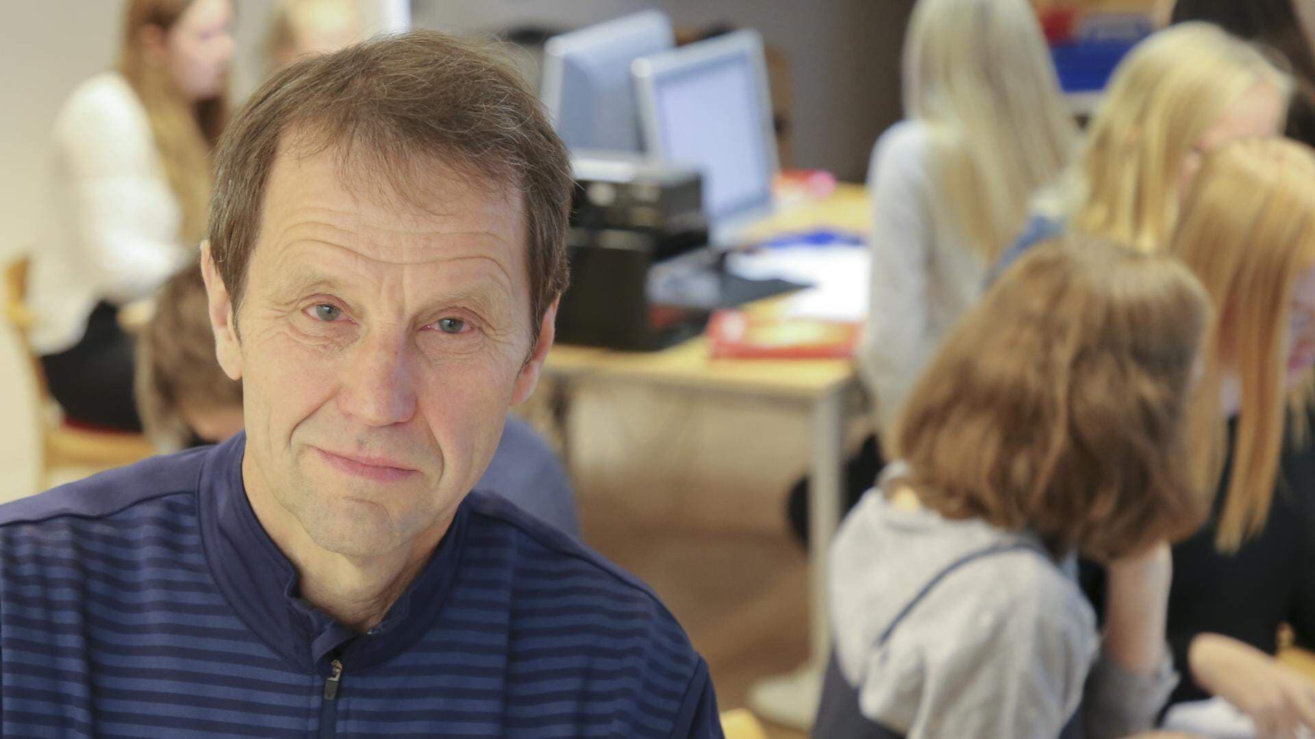 Jan Nordin i ett klassrum, skolelever arbetar i bakgrunden.