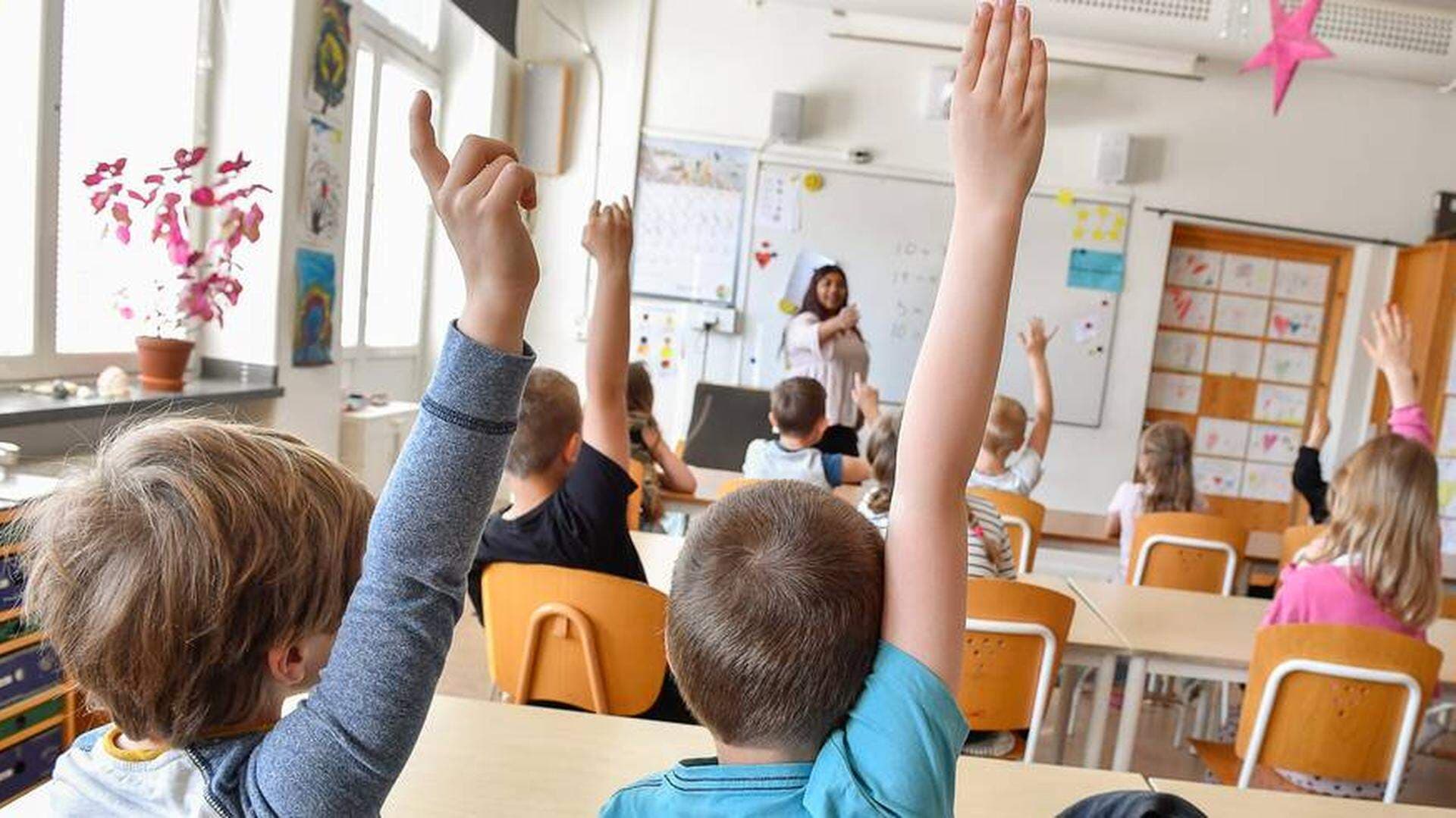Barn räcker upp hönder i ett klassrum