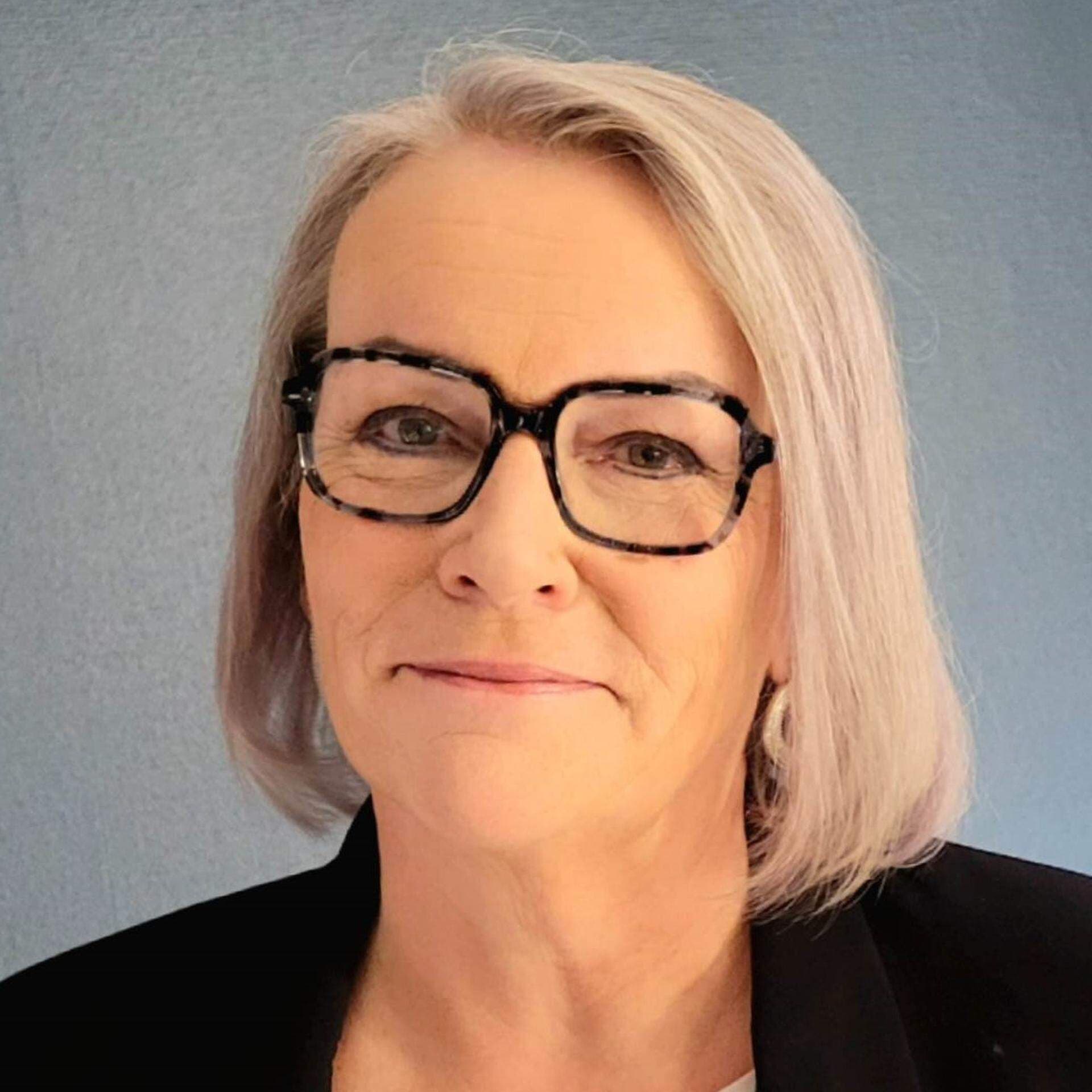 Margareta med svarta, fyrkantiga glasögon, vit topp och svart kavaj