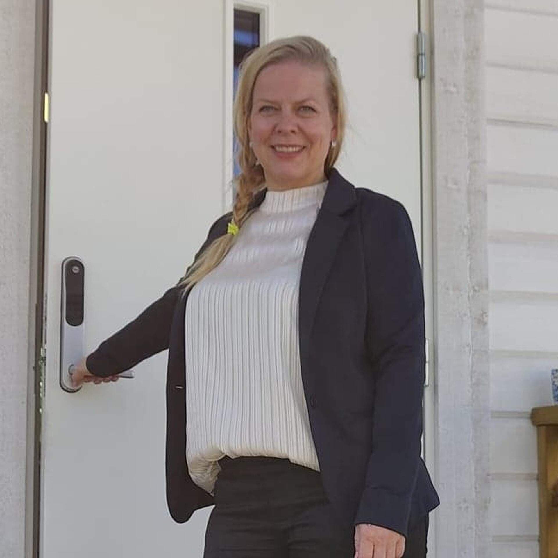 Elisabeth Landby står på en trappa vid en öppen dörr