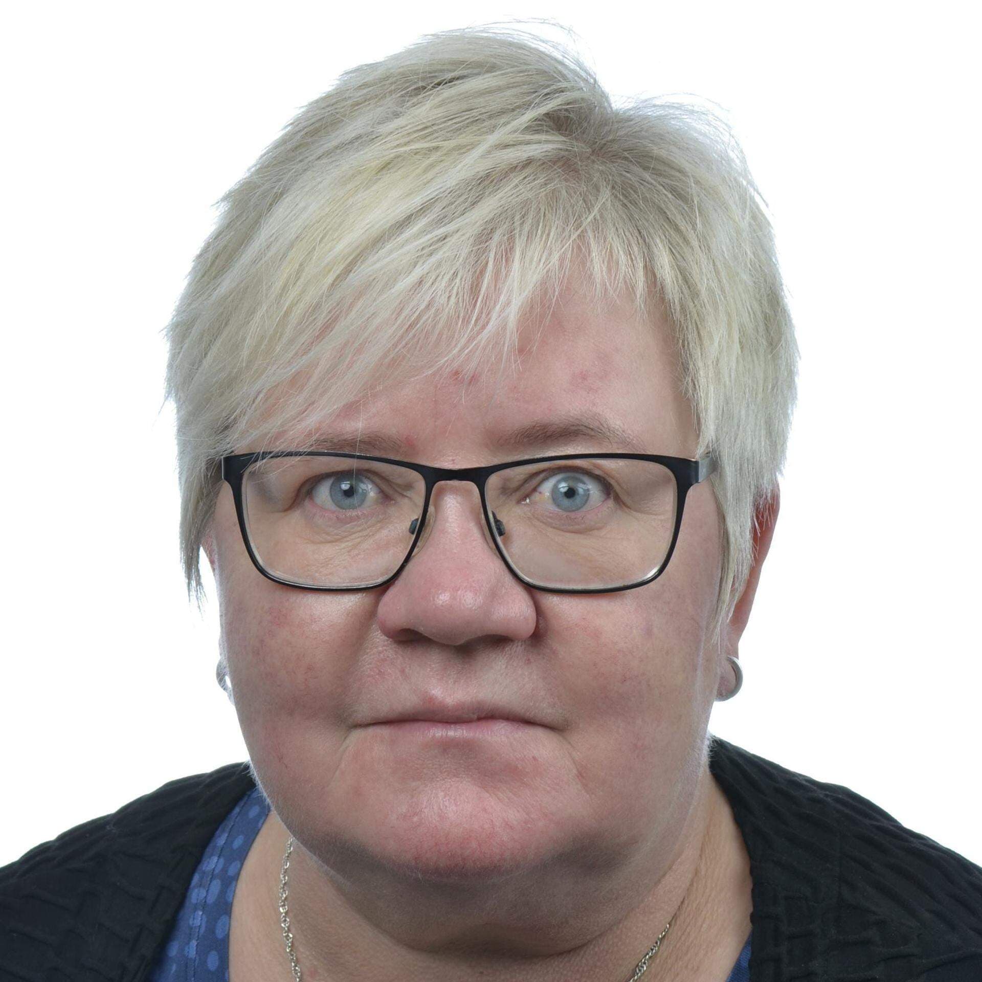 Caroline i blå topp med små, vita blommor och en mörkblå kofta.