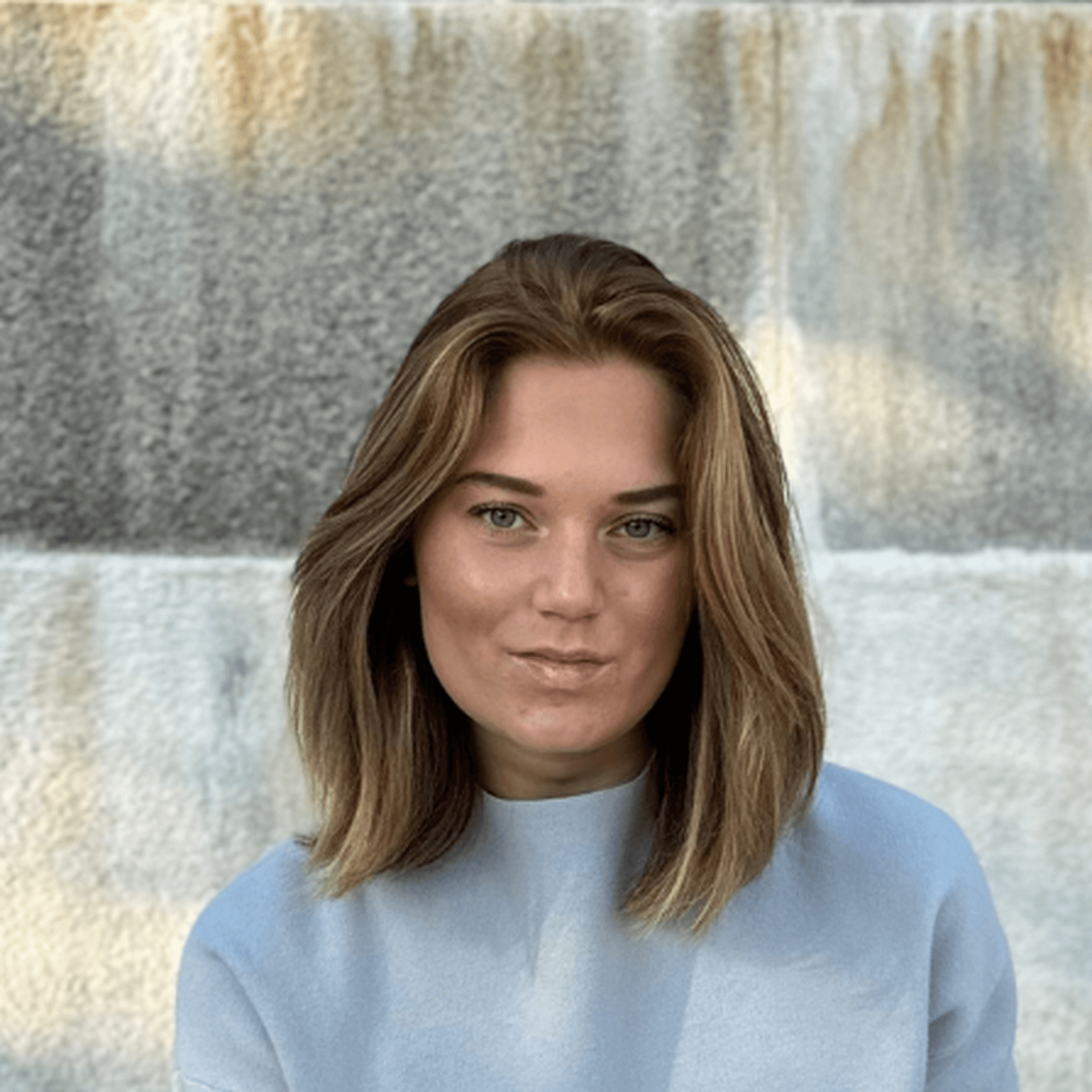 Louise i ljusa kläder sittandes på en grön parkbänk