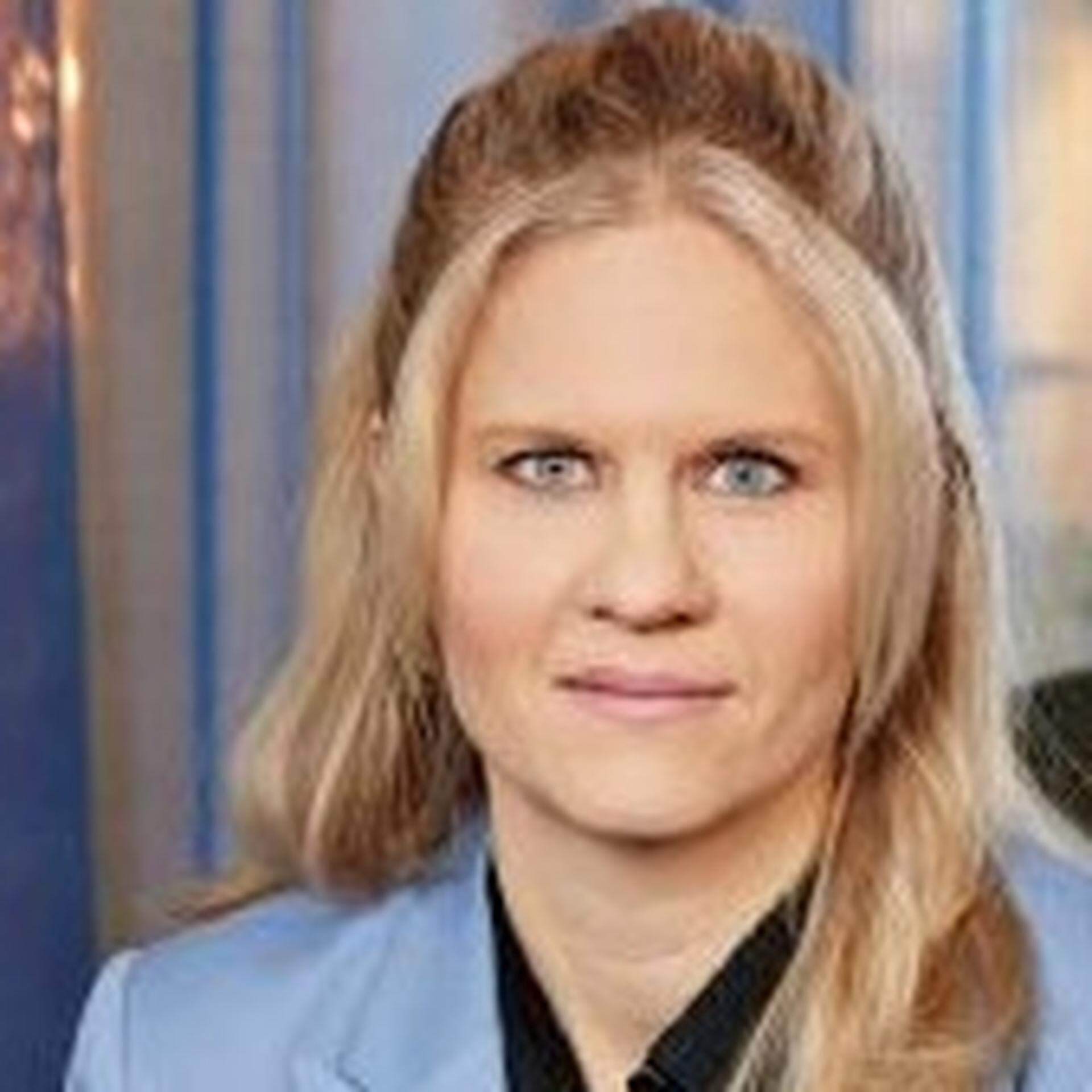 Charlotta iklädd mörkblå blus och ljusblå kavaj