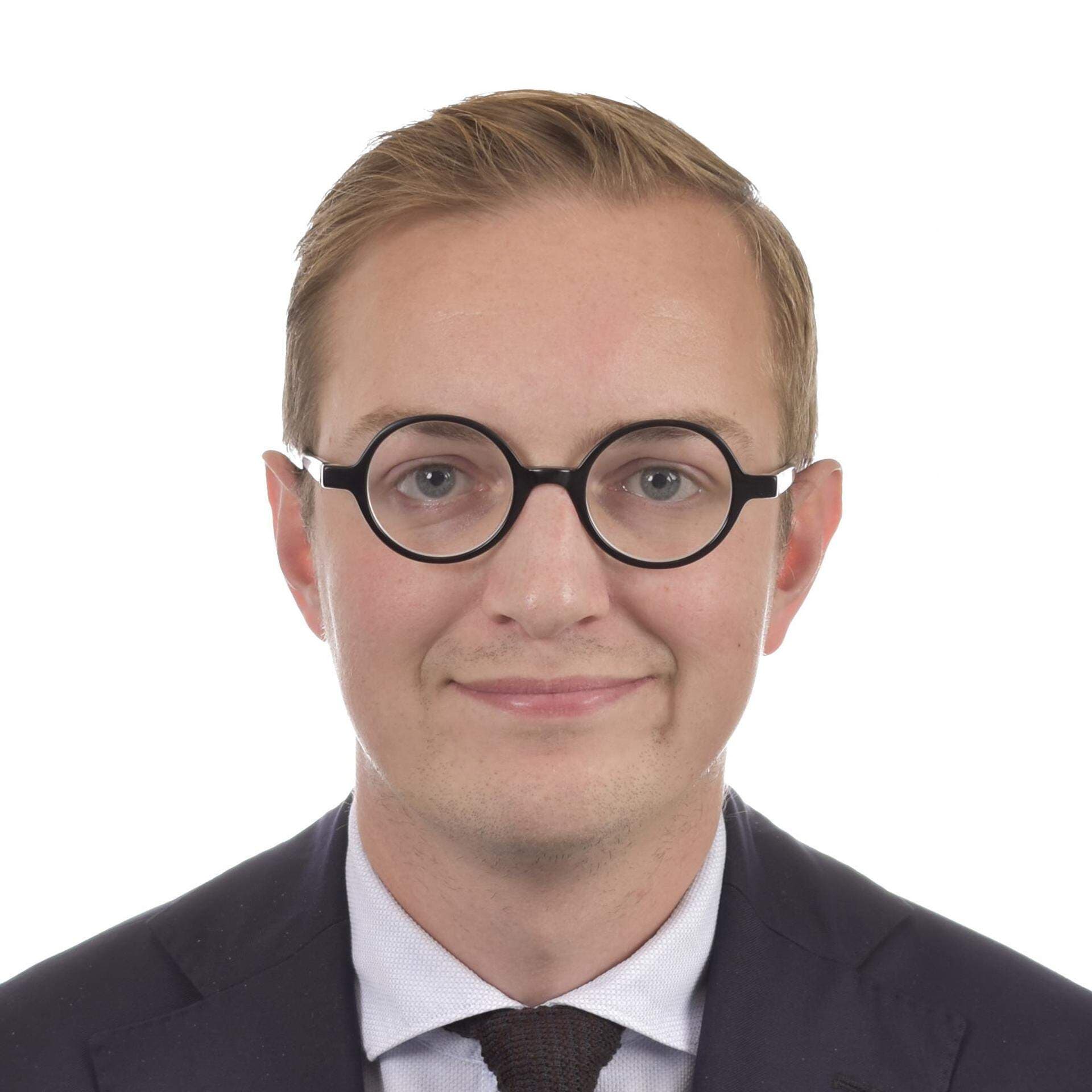 Jonny Cato i vid skjorta, svart slips och mörkblå kavaj