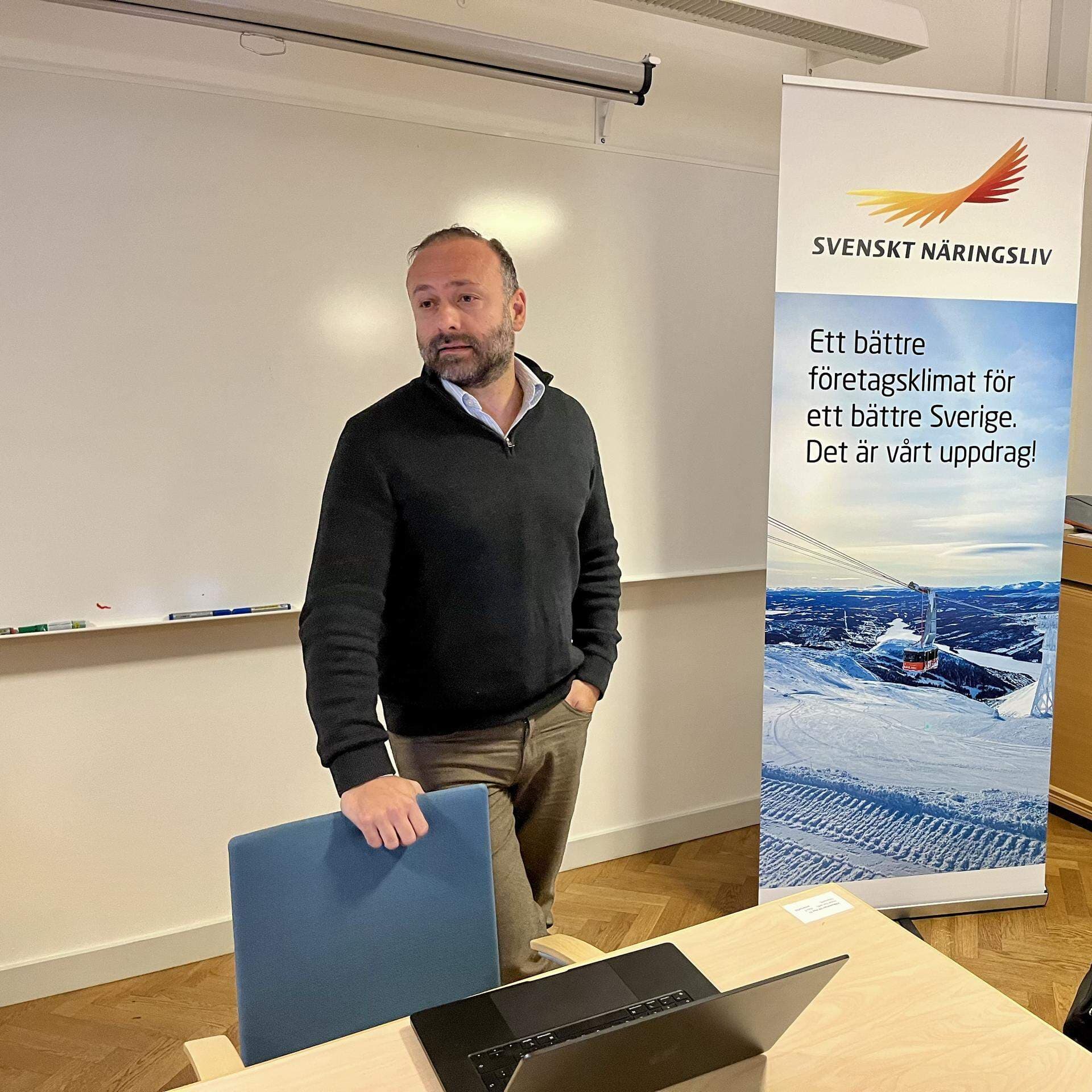 Alee Farrohi, huvudman och en av delägarna i Honesta skolutveckling, står i ett konferensrum och har på sig en svart tröja.