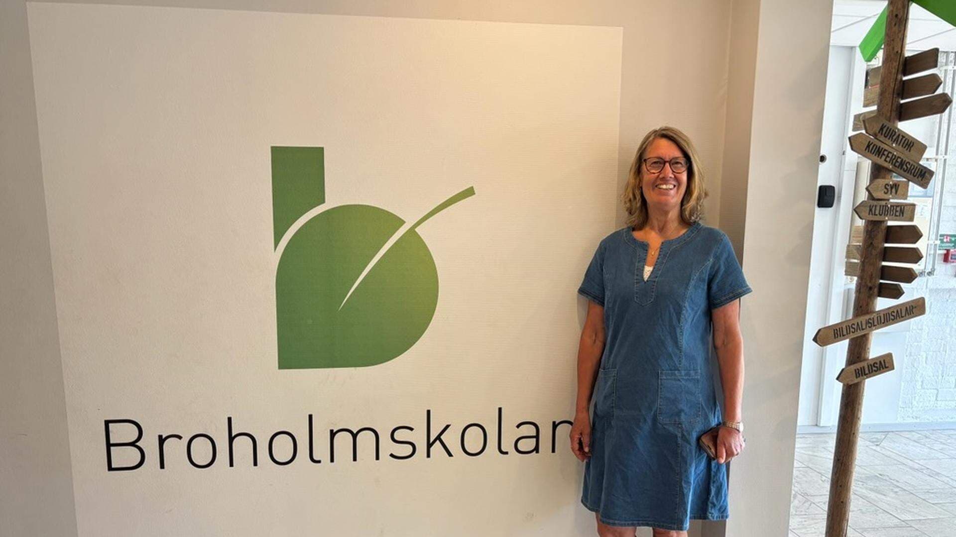 Marie Pilfalk framför skylt Broholmsskolan
