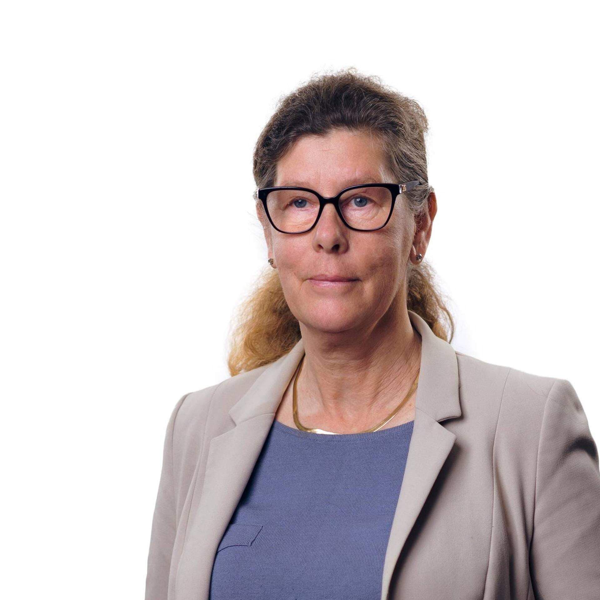 Edit Karlsson Håål i blå topp och grå kavaj. Bakgrunden är vit.