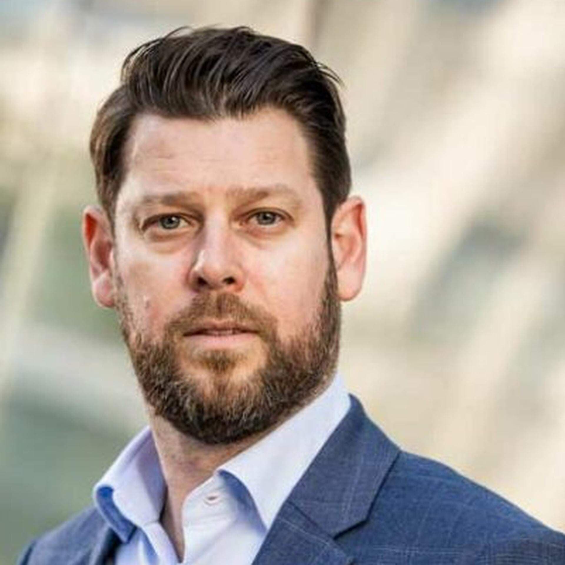 Jonas i stadsmiljö iklädd ljusblå skjorta och mörkblå kavaj