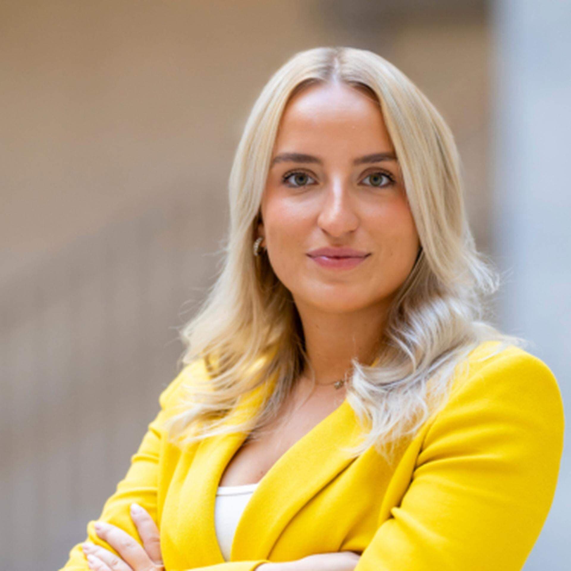 Denice med armarna i kors iklädd gul kavaj