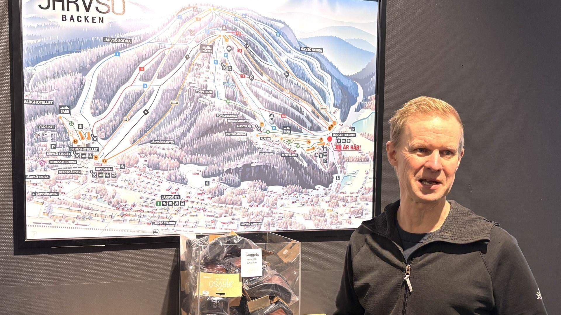 Peter Augustsson, delägare och vd för Järvsöbacken står framför en bild av Järvsöbacken.