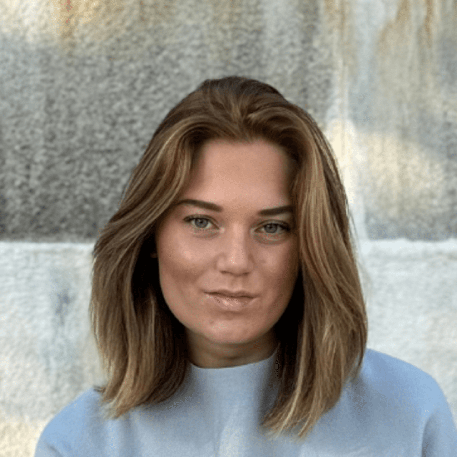 Louise i ljusa kläder sittandes på en grön parkbänk