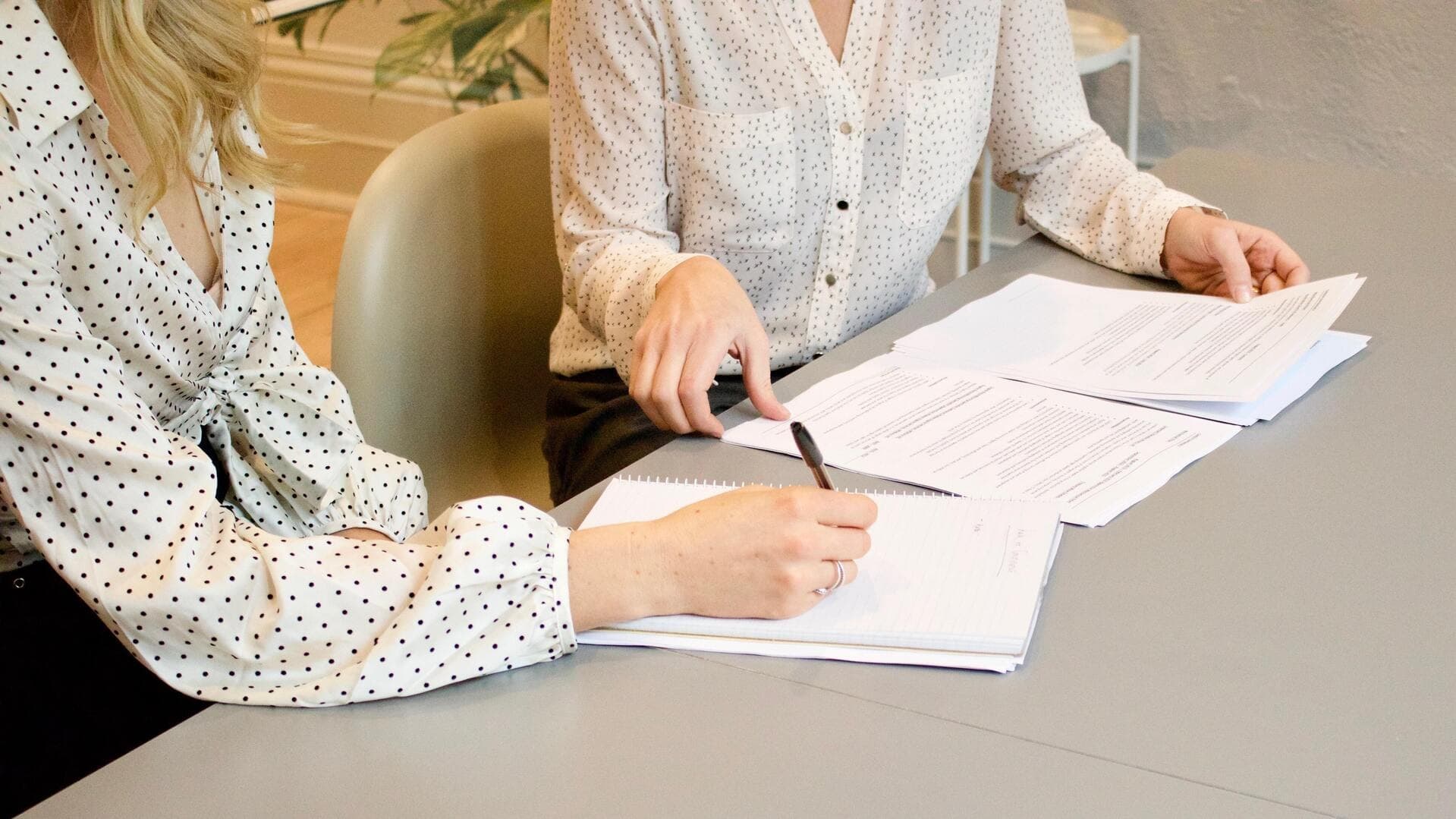 Två kvinnor sitter vid ett bord och går igenom en hög med papper
