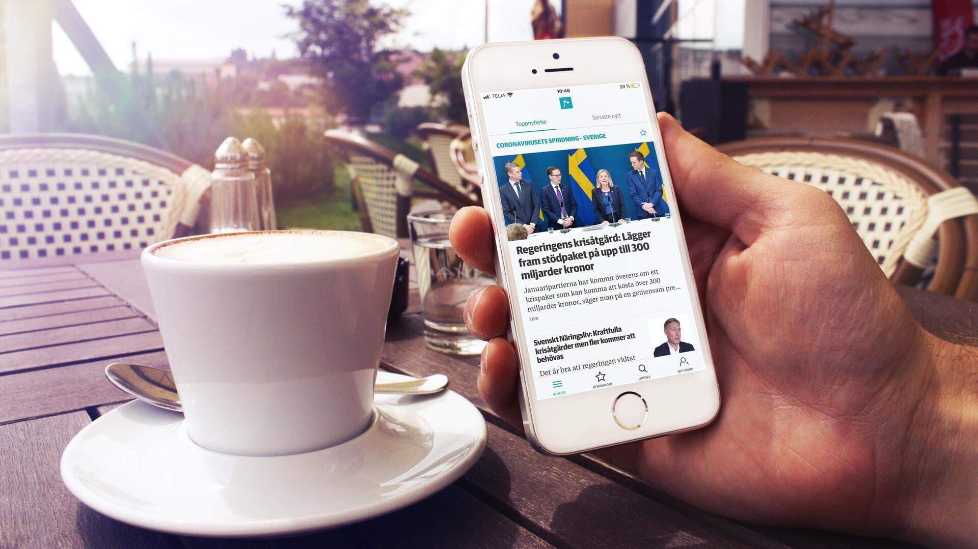 iPhone som visar fPlus app vid ett fikabord.