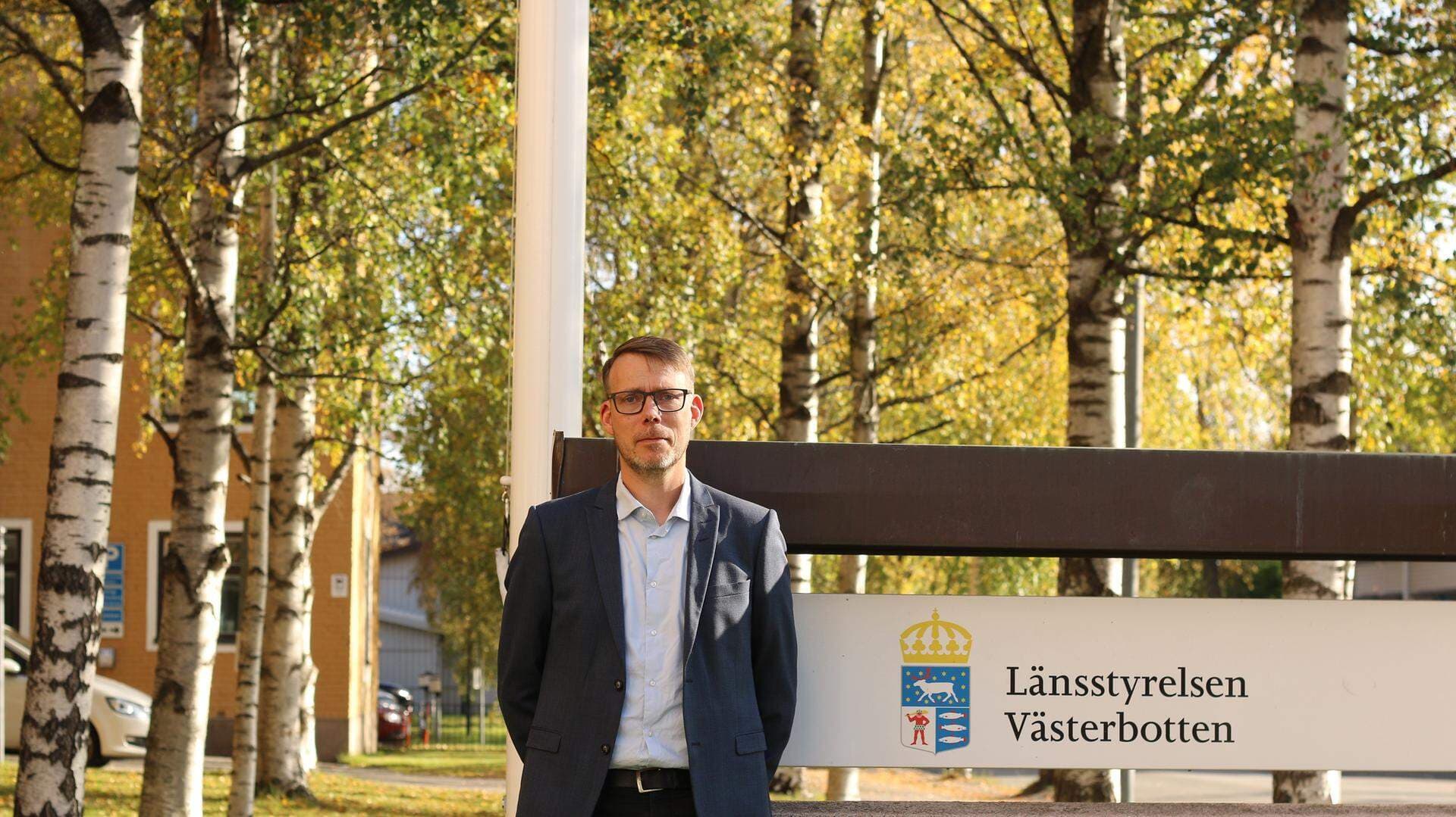 Magnus Langendoen står utomhus framför en skylt med Länsstyrelsen i Västerbottens logotyp.