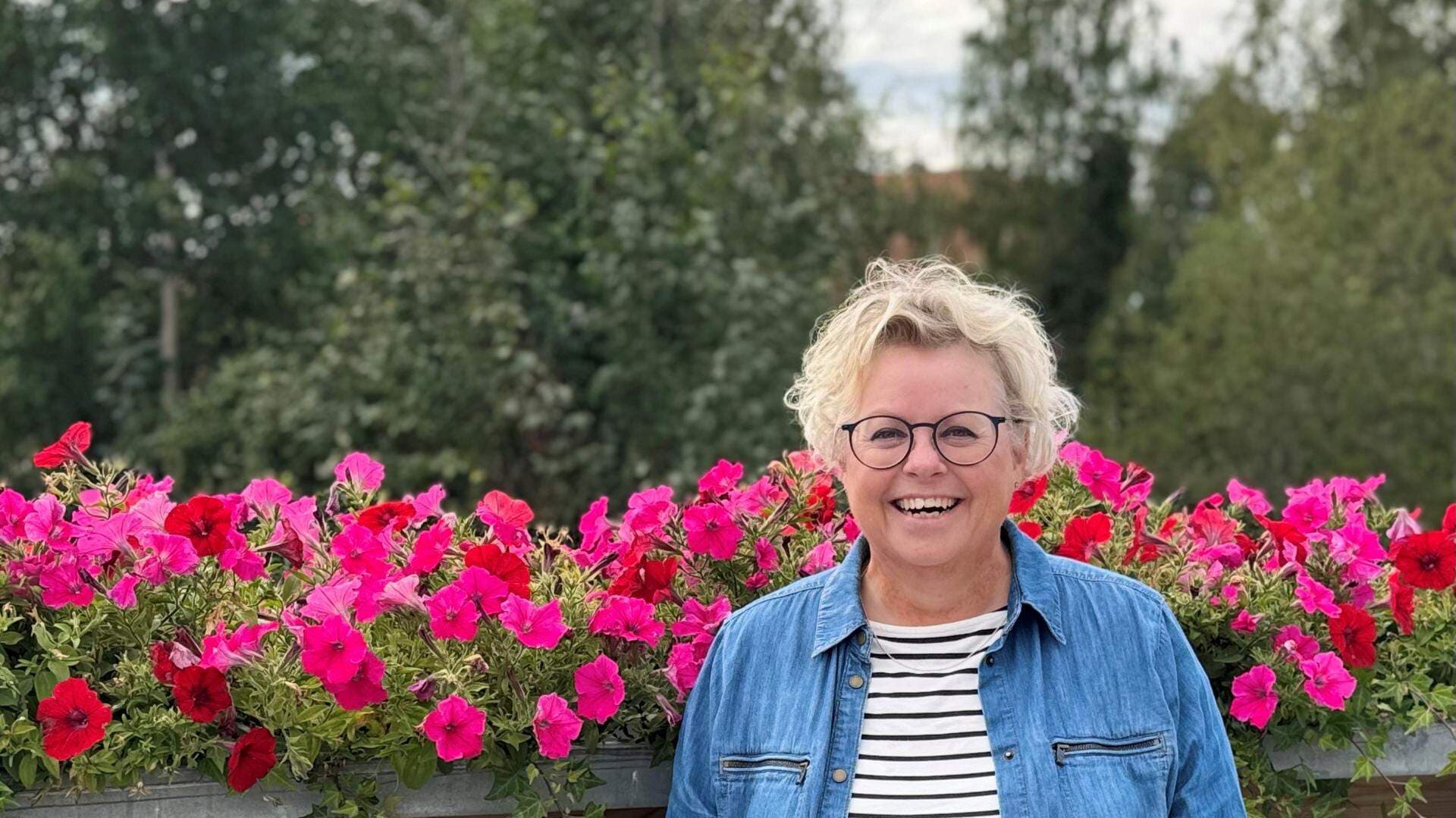 Anna Lindberg, kommunchef i Älvsbyn, står utomhus med blommor i bakgrunden.