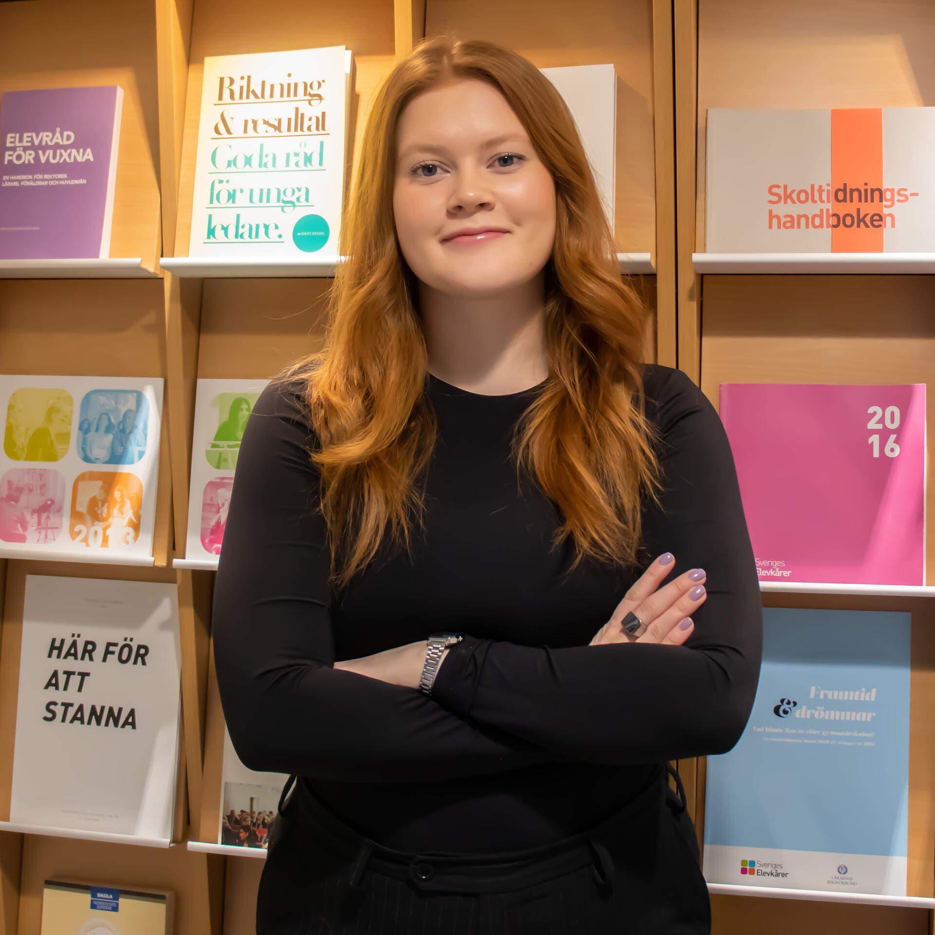 Bild på Embla Persson vid en bokhylla