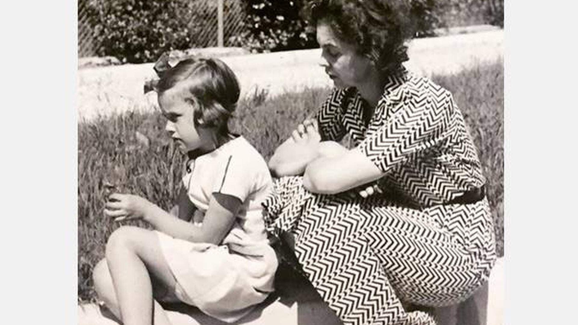 Kvinna och liten flicka som väntar på tåget på en trottoarkant i Slite