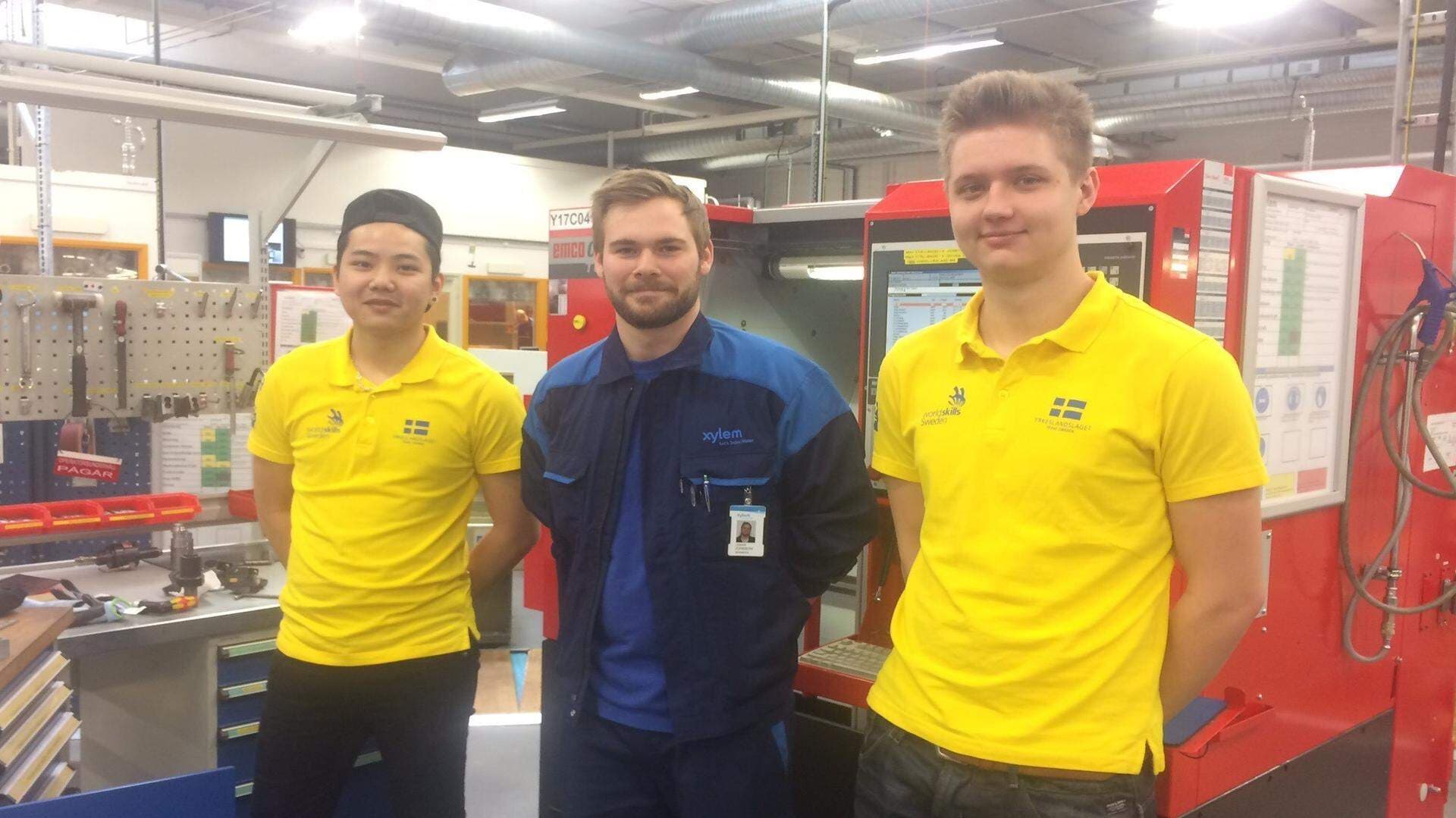 två gulklädda personer tillsammans med handledare bland industridatorer