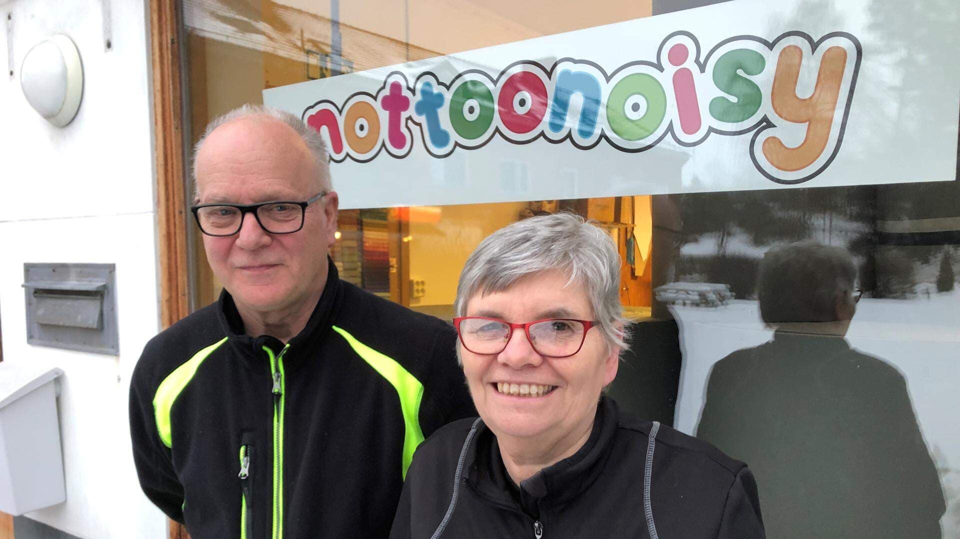 två ägare framför fönster med logga på närmare