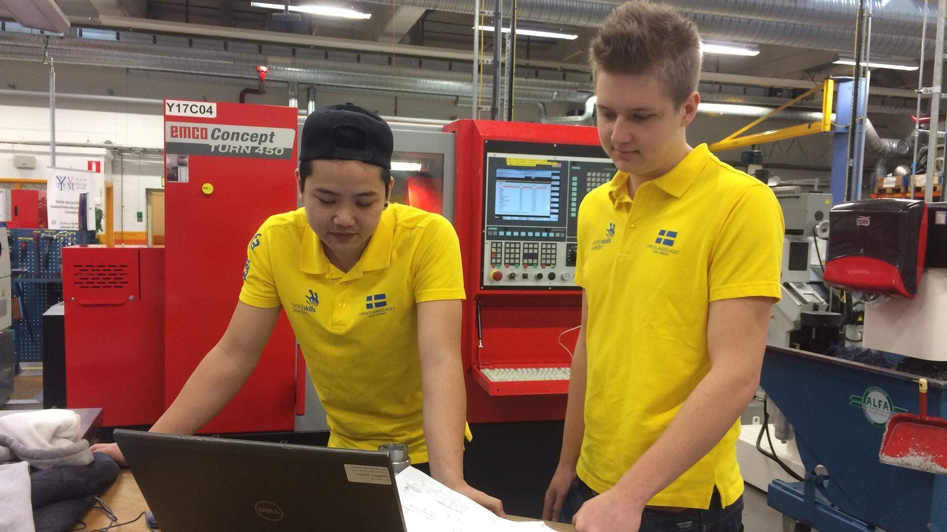 två gulklädda personer bland industridatorer