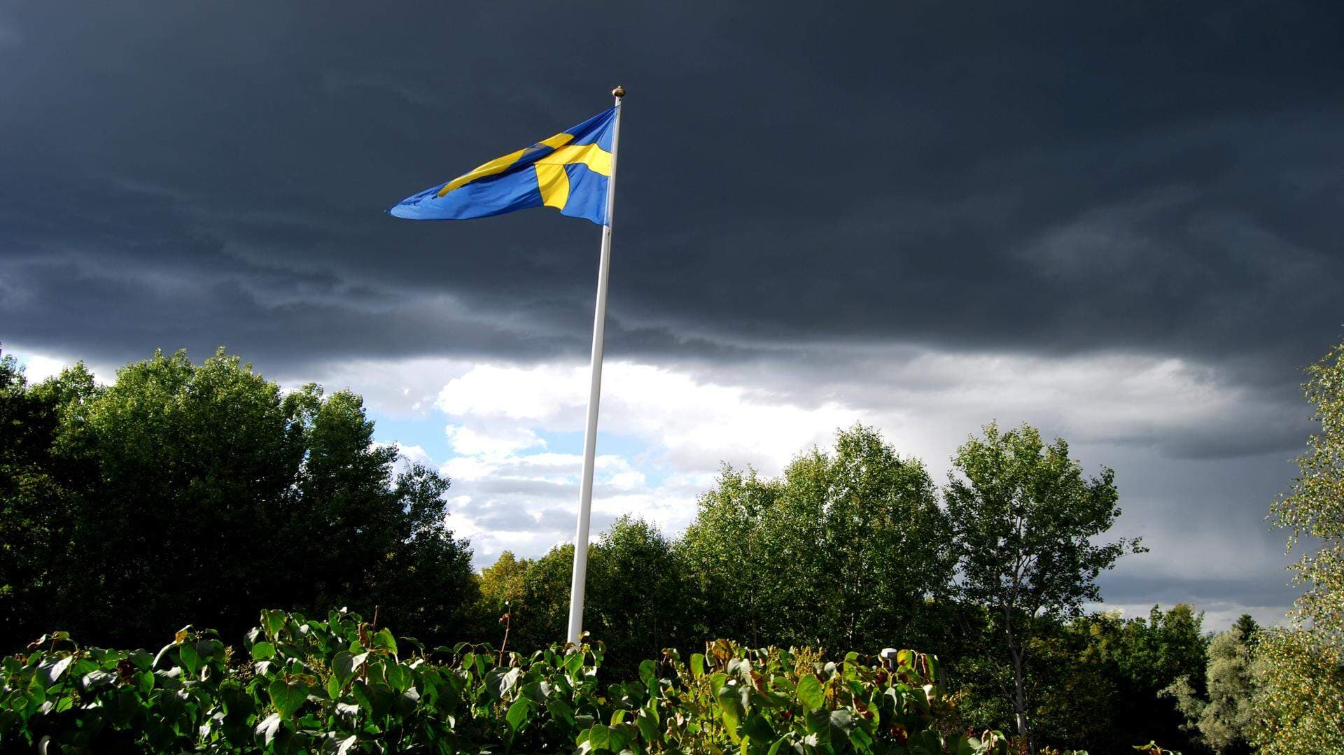 Svenska flaggan med mörka moln