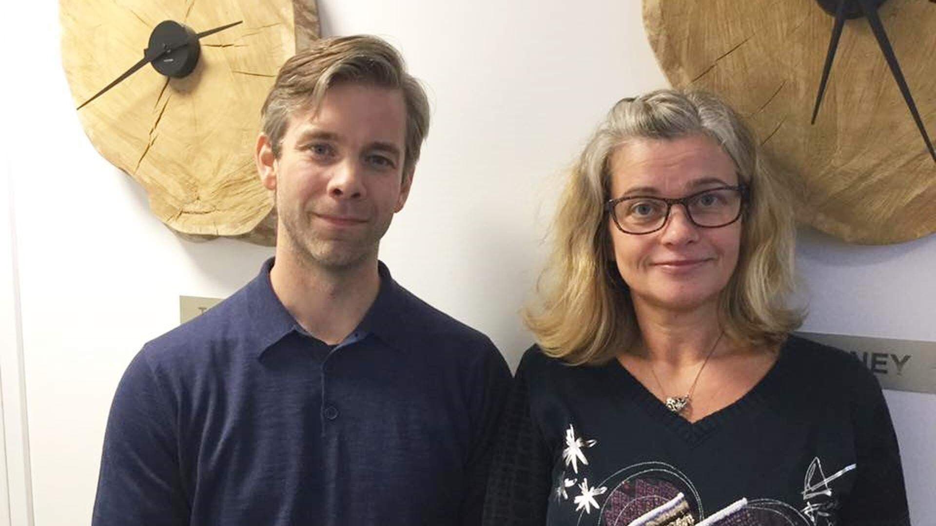två personer framför två träklockor