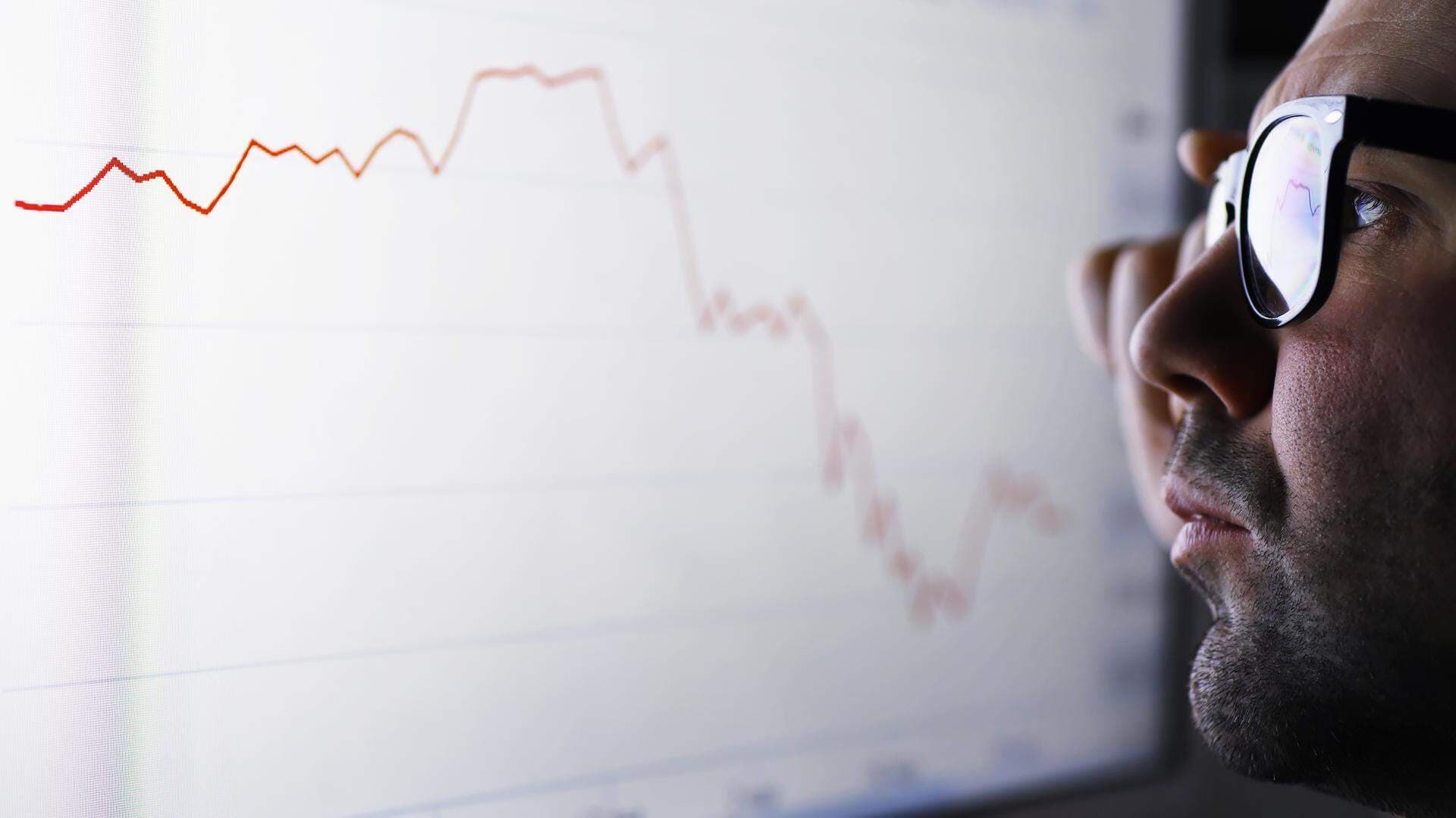 En affärsman som tittar på en skärm med fallande graf
