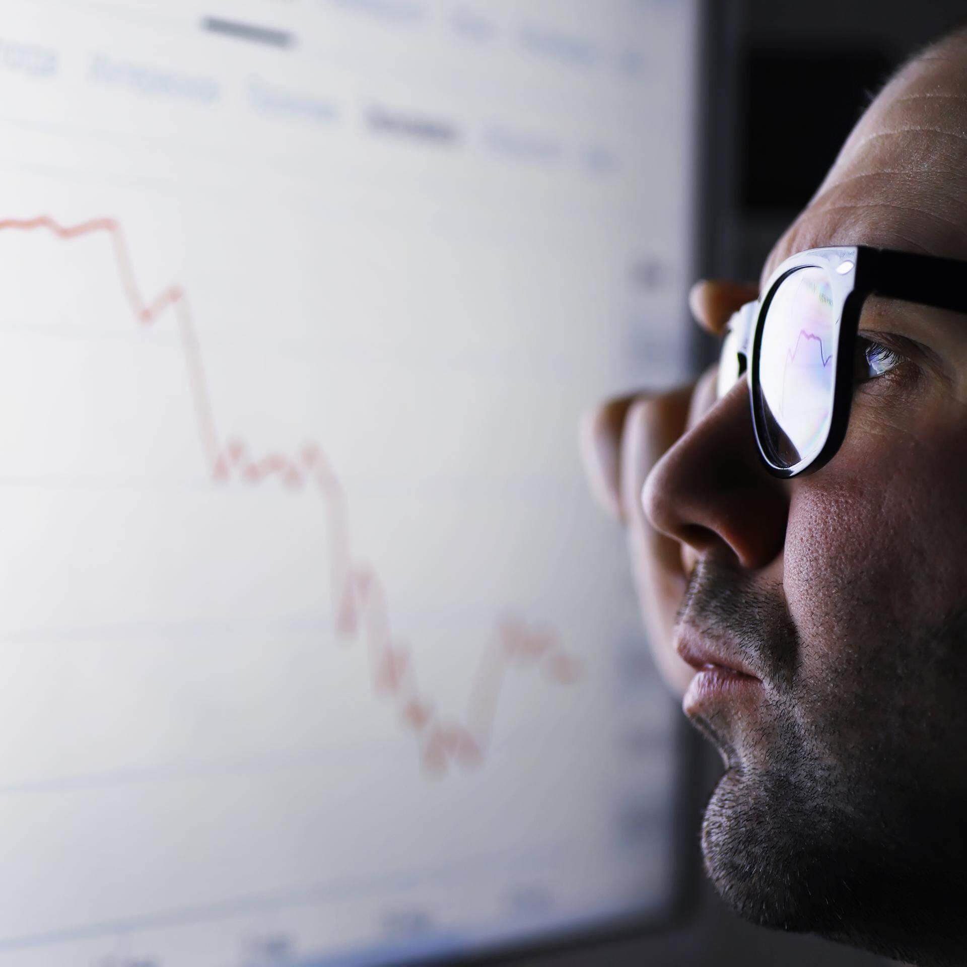 En affärsman som tittar på en skärm med fallande graf