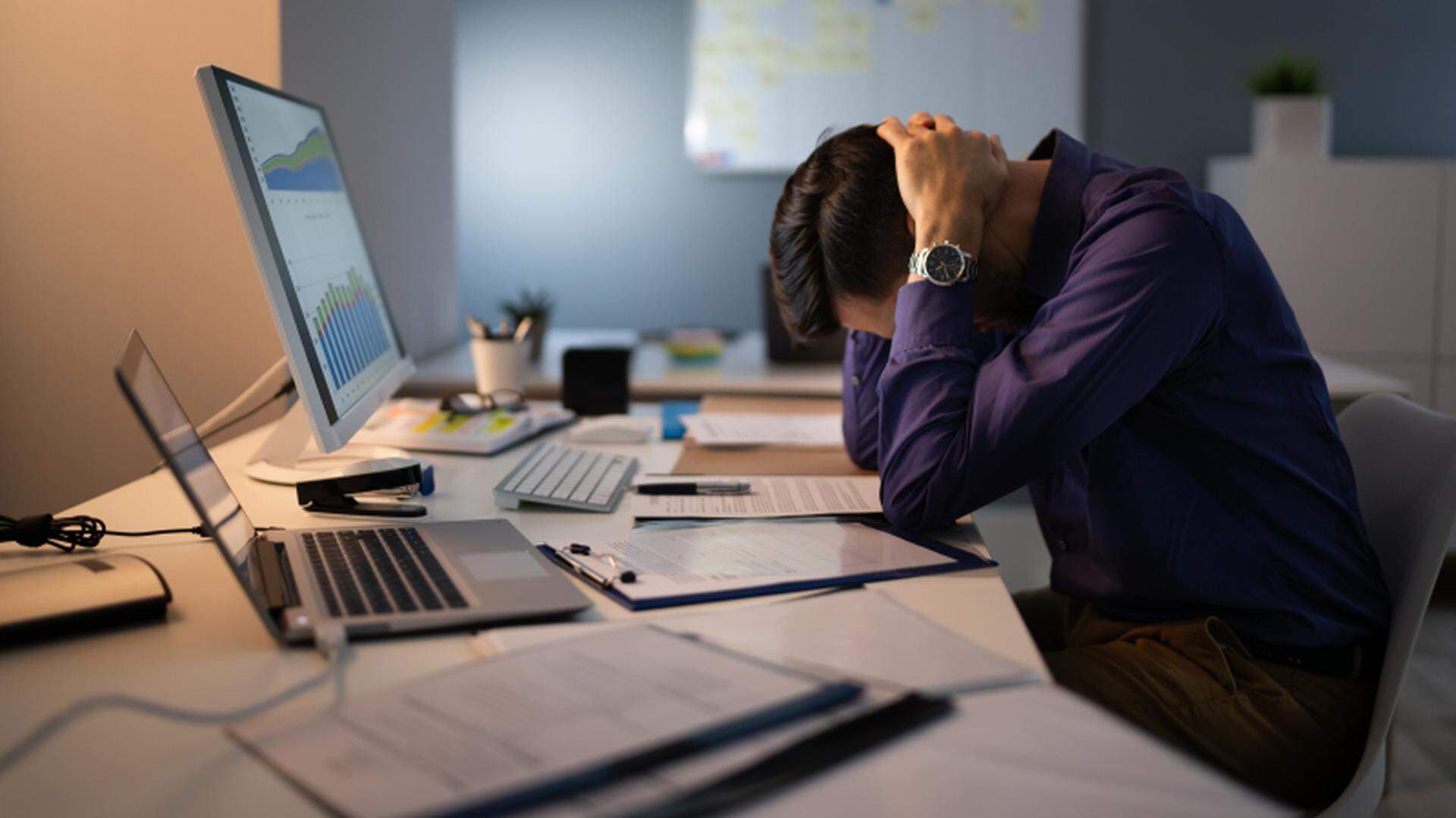 En man hänger över ett skrivbord fullt med dokument