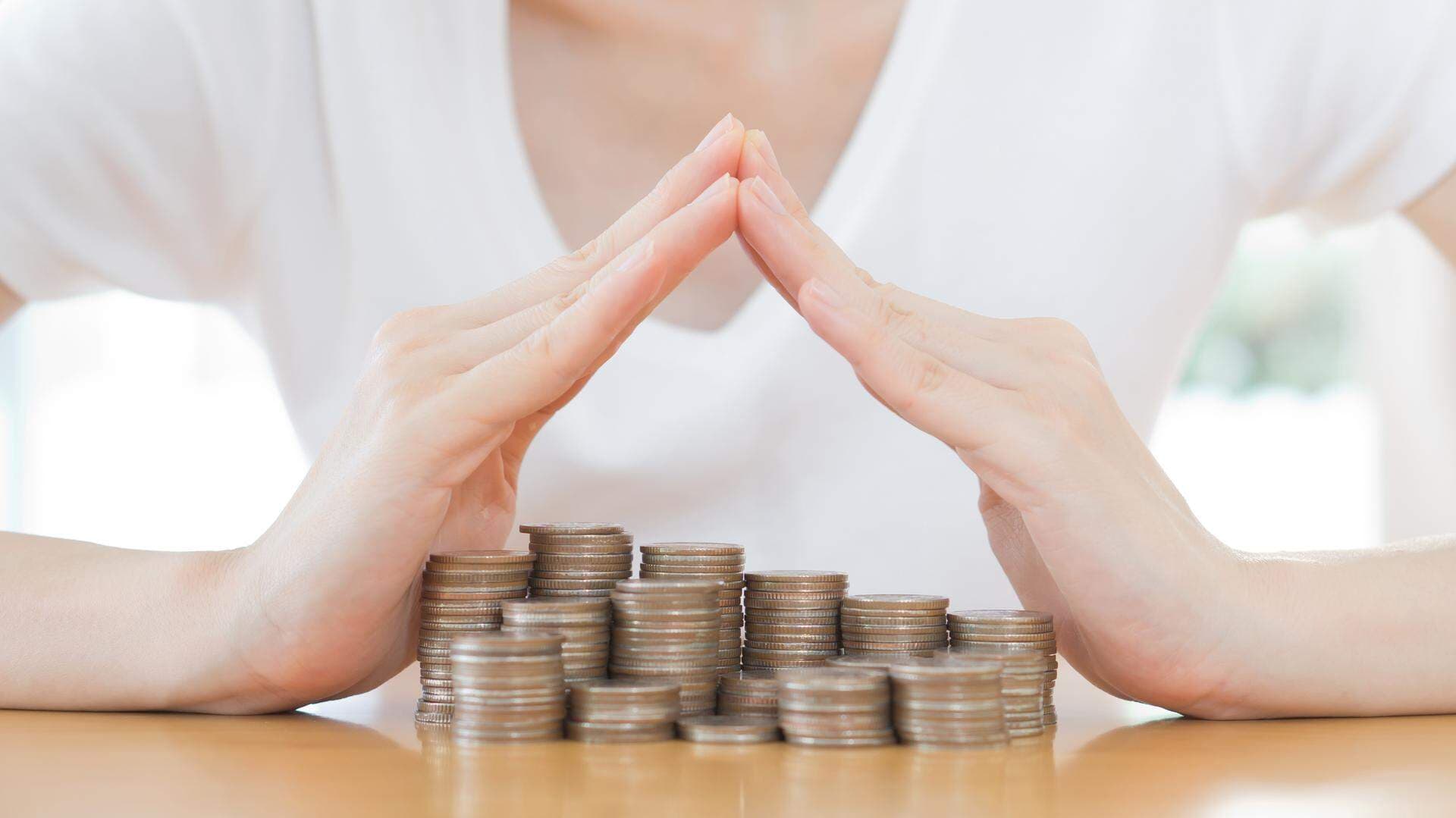 två händer kupade över mynthögar