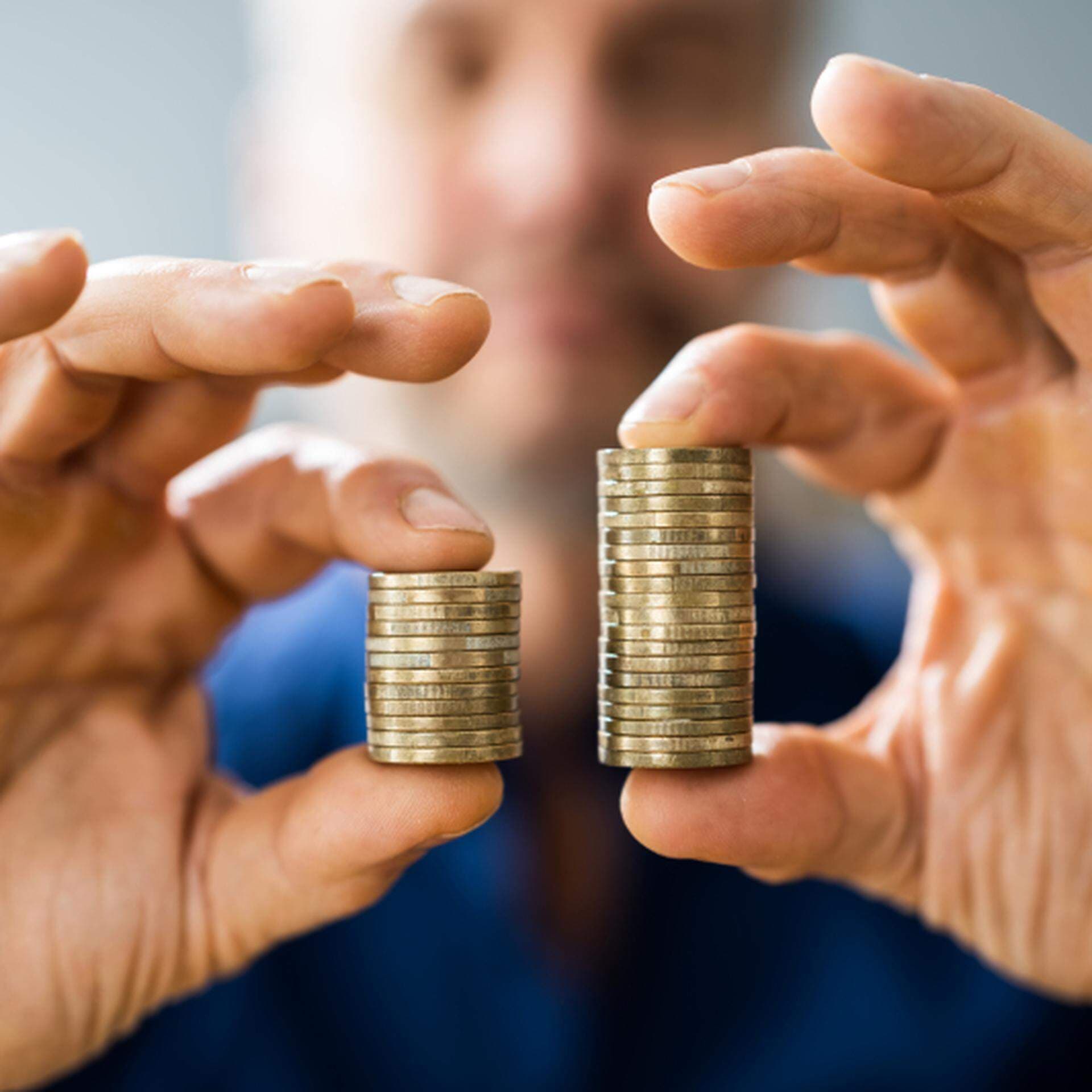 Två händer som håller fram två mynthögar