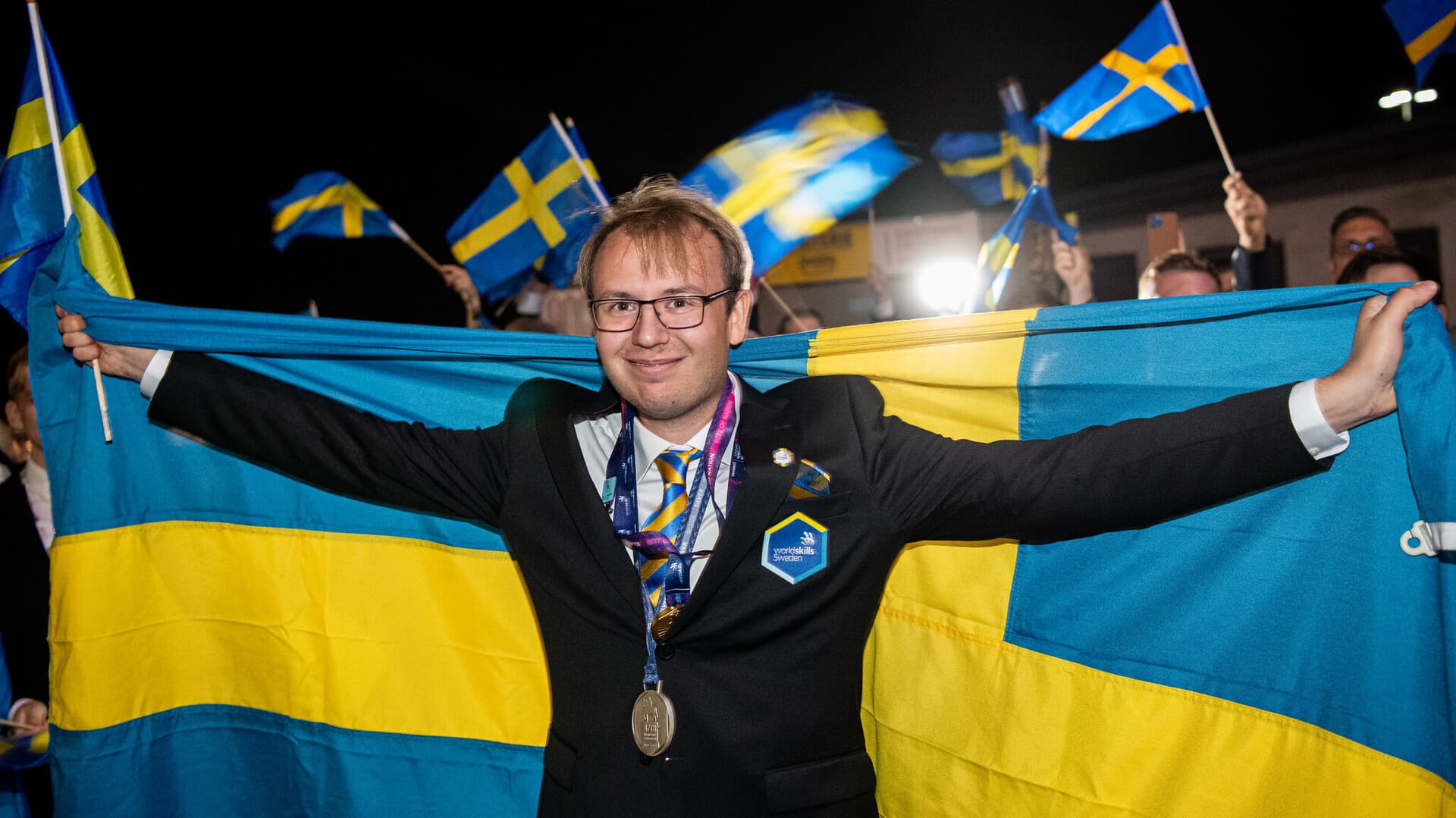 Bilden föreställer Fredrik Cederlöw under yrkes-VM tillsammans med sin silvermedalj och en svensk flagga.