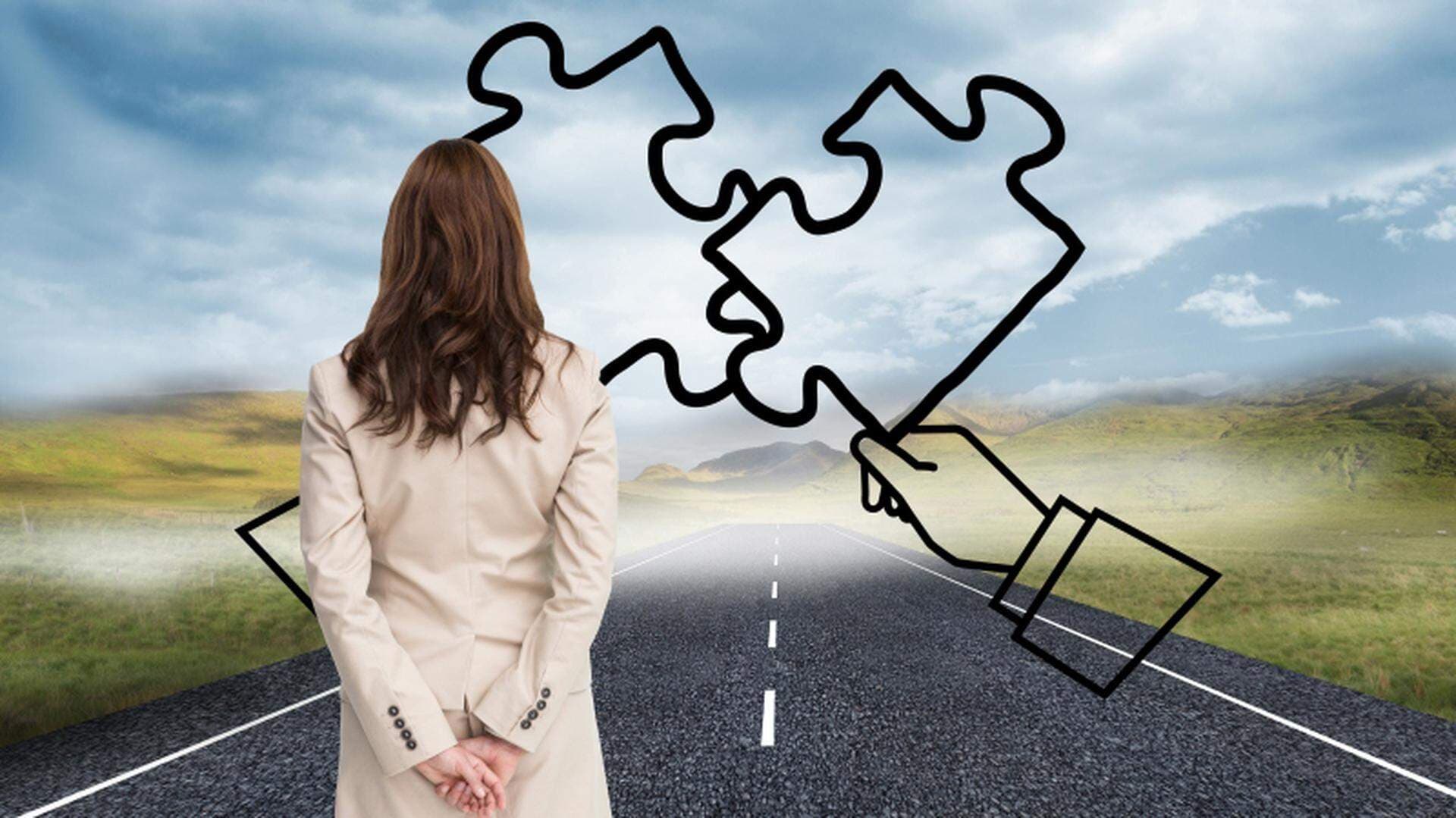 kvinna sedd bakifrån ståendes på en vägg med två ritade pusselbitar framför sig på en grå himmel