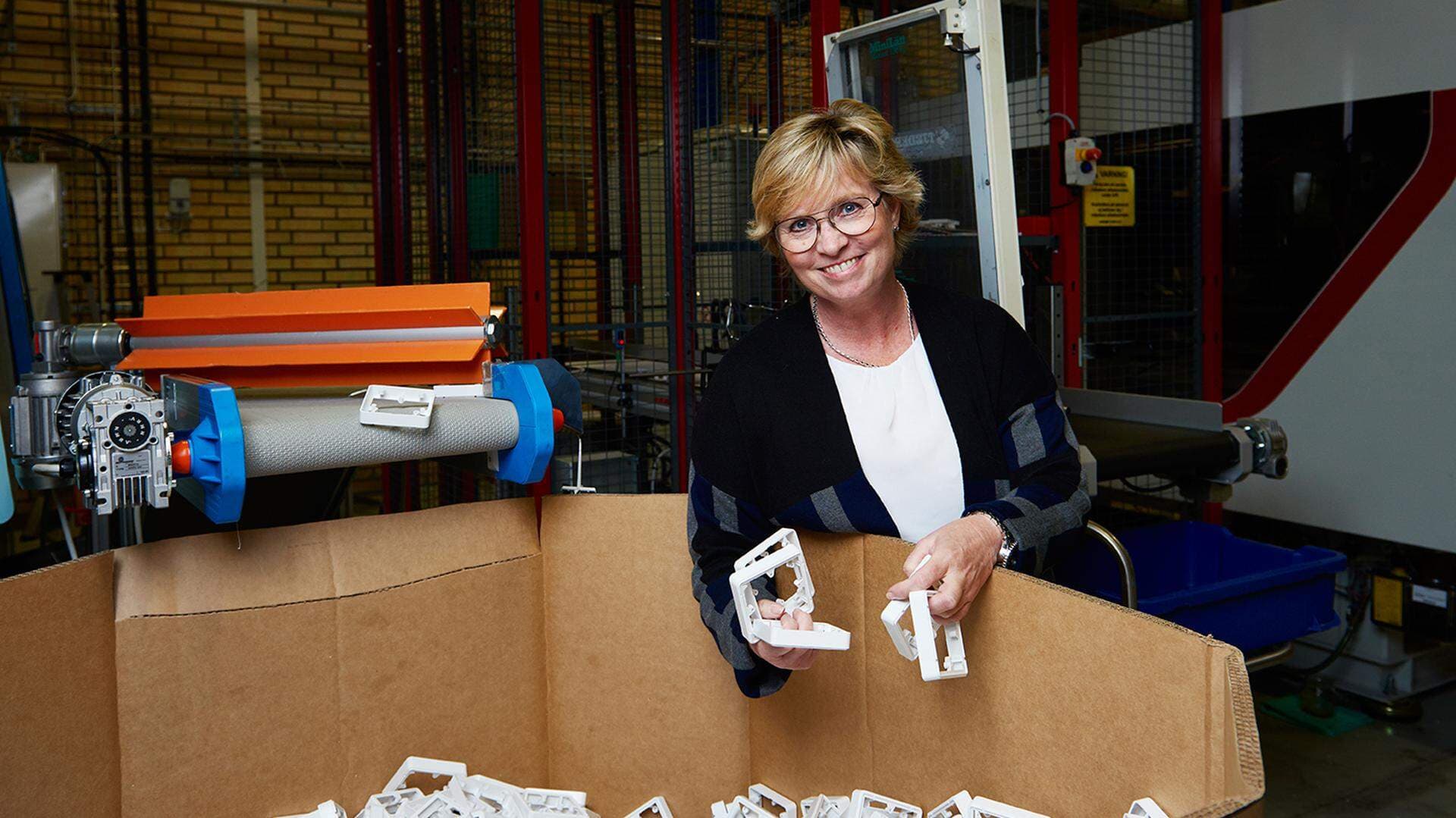 Marie Svensson i produktionen vid en stor kartong med plastlock