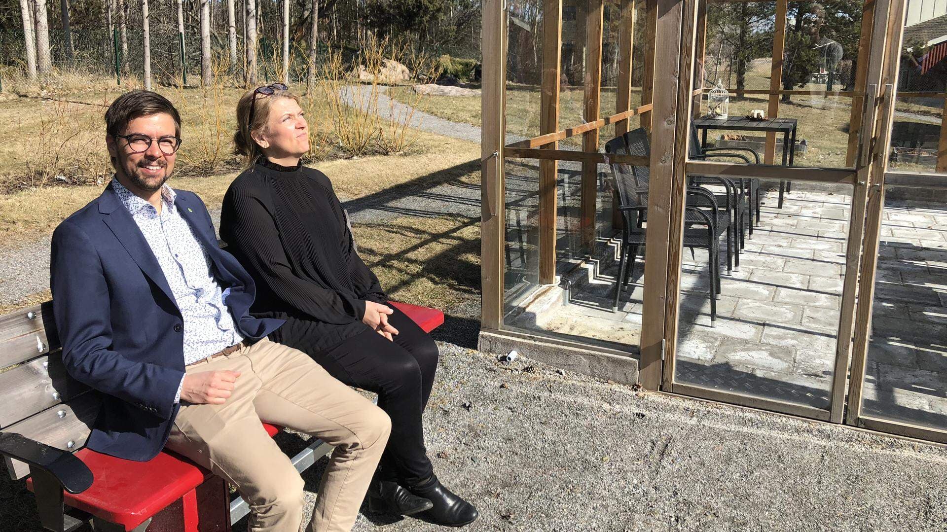 Linus Lakso och Marielle Lahti tar igen sig på en bänk framför Attendos växthus.