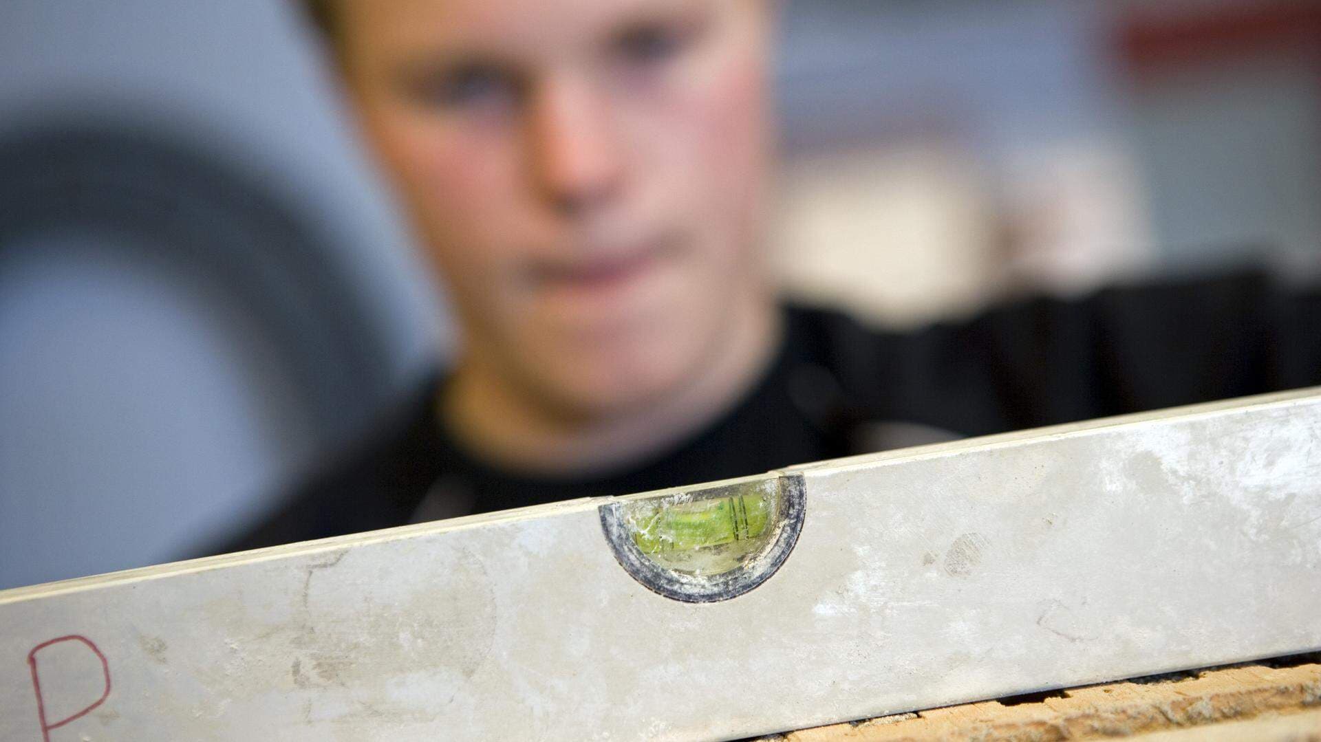 En elev på bygg- och hantverksprogram som använder ett vattenpass