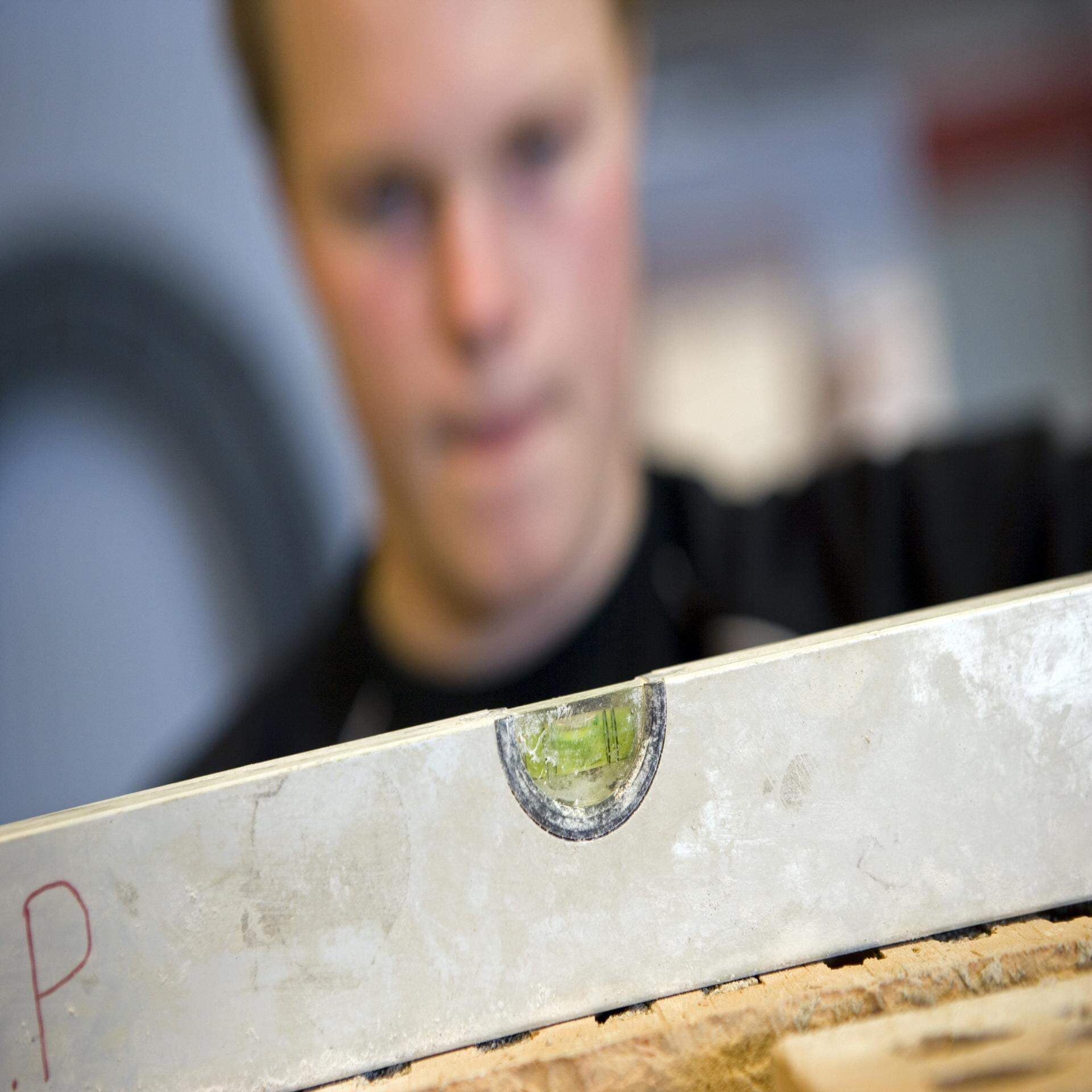 En elev på bygg- och hantverksprogram som använder ett vattenpass