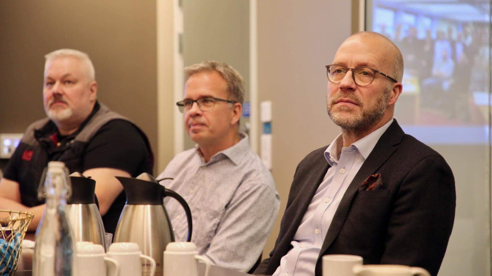 Tre män som sitter vid ett konferensbord