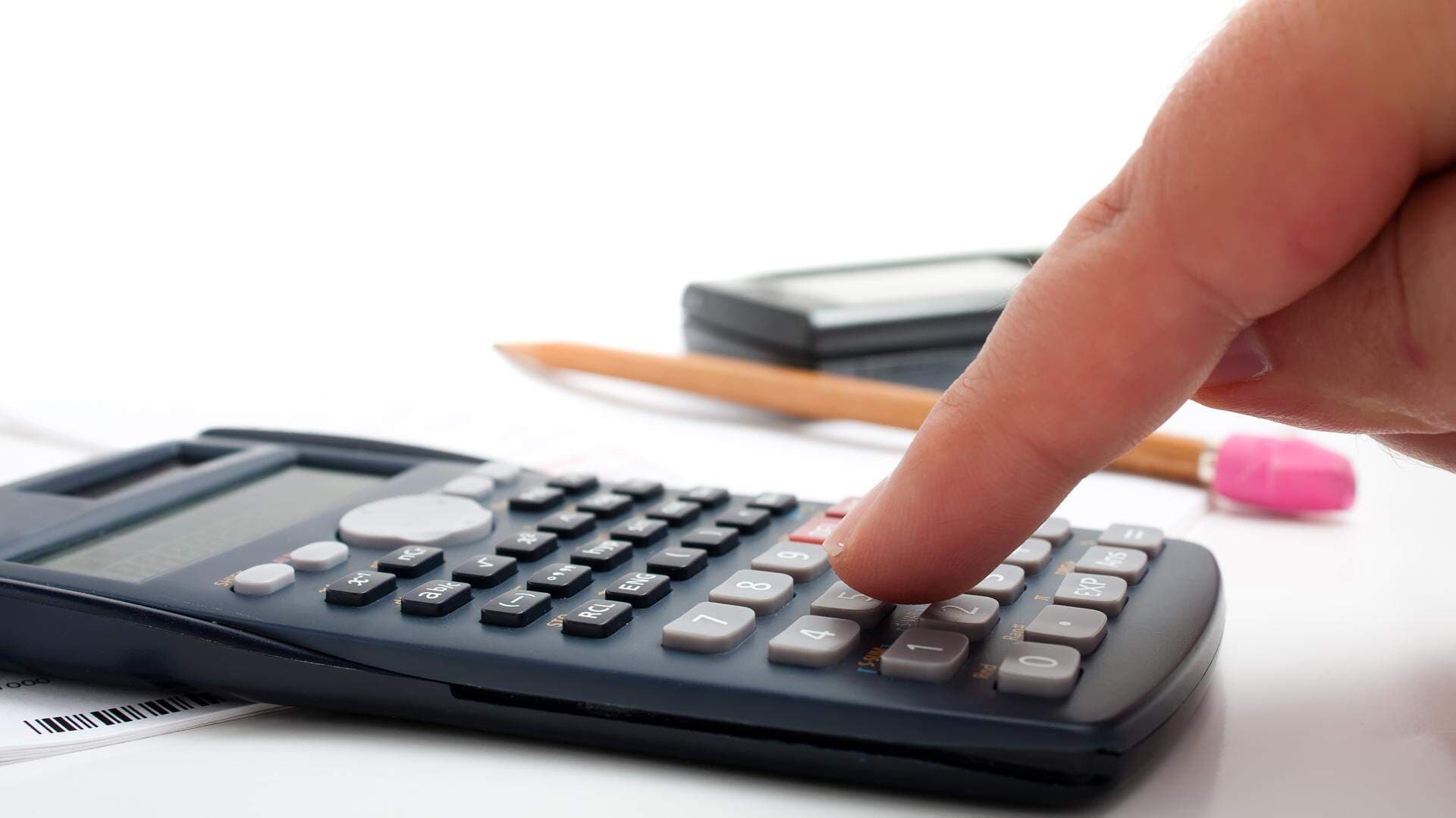 Finger som slår på en miniräknare