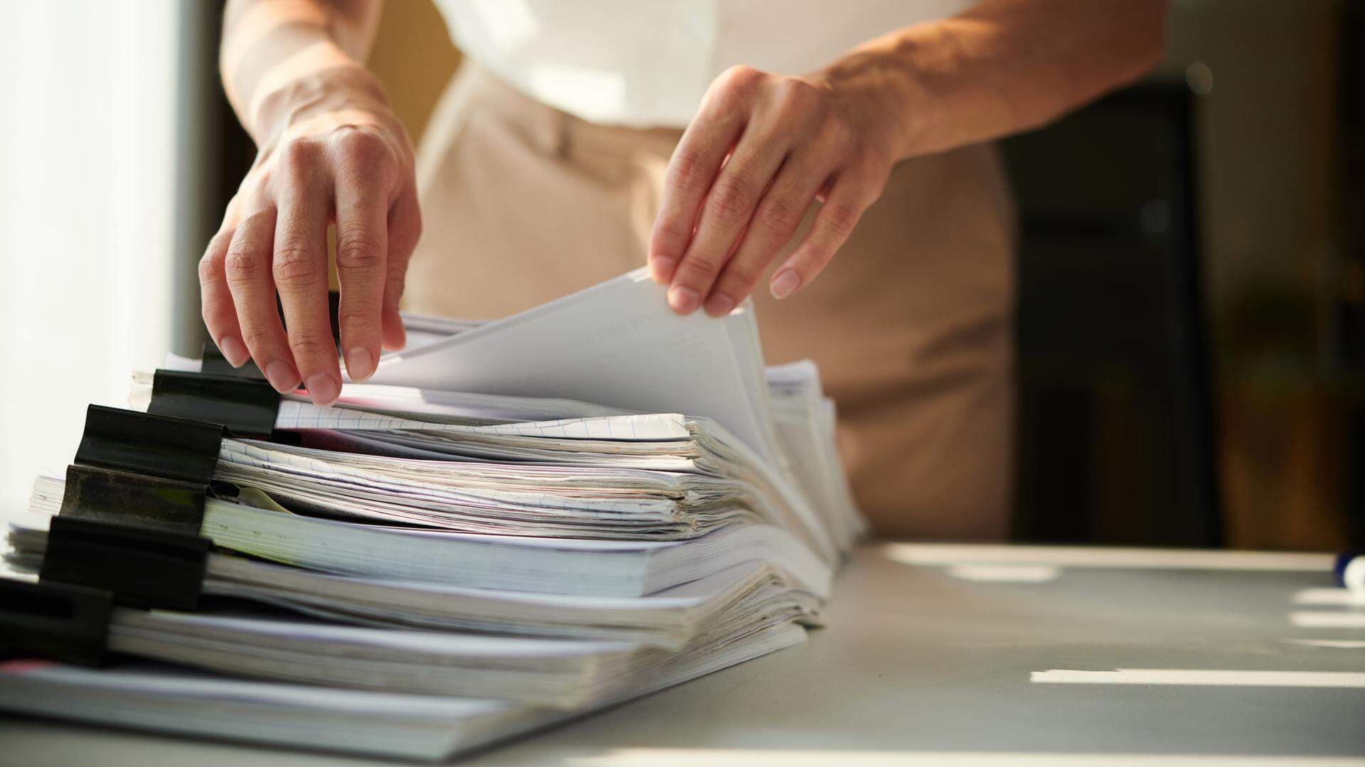 Kvinna som bläddrar i en hög av papper