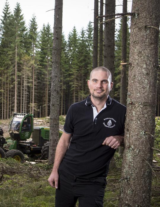 Håkan Nilsson lutar sig mot ett träd i en skog 